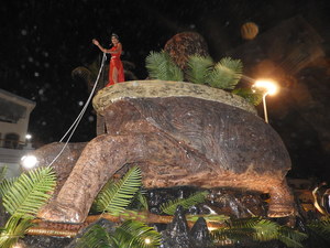 Woman perched on giant tortoise parade float