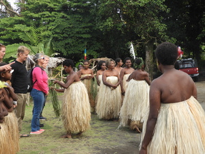 Women in grass skirts presenting welcome leis to visitors