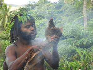 Man holding smouldering coconut husk fibres.