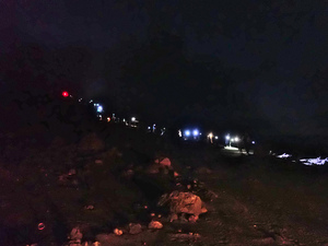 Long line of headlamps and flashlights snaking down path from top of crater