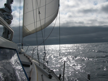 Passing from sunny seas under darker clouds