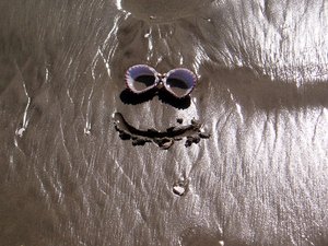 Smiley face scribed in sand with shell eyes